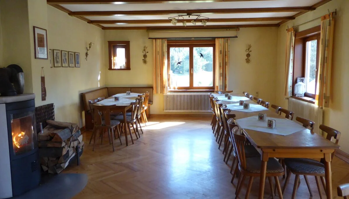 Das Bild zeigt den Innenraum des Rudolf-Keller-Hauses. Der Kamin brennt. Mehrere Tische sind bestuhlt. | © DAV